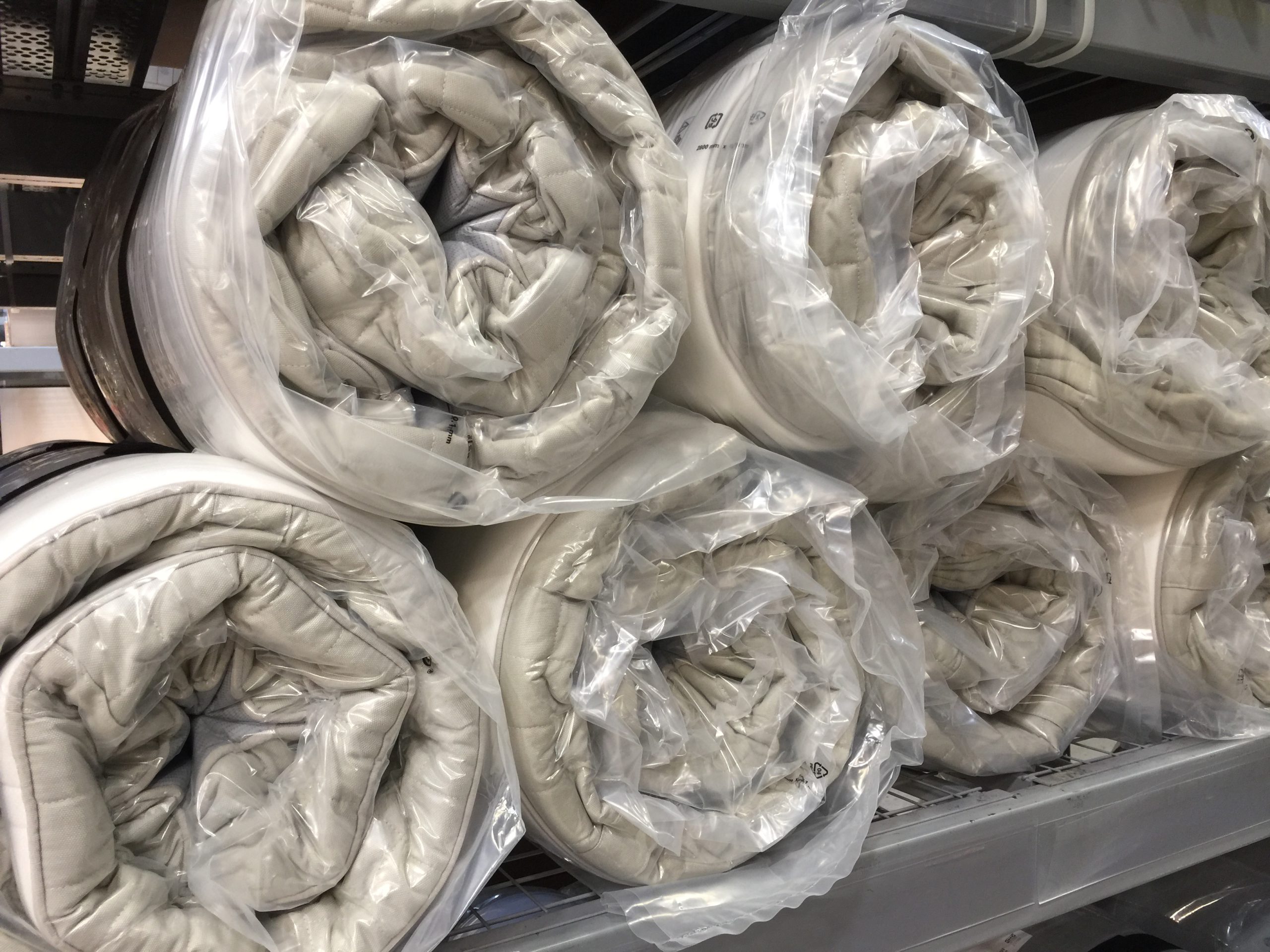 A compressed and rolled mattress on a warehouse shelf