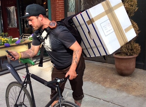 A man delivering a mattress in a box on a bicycle